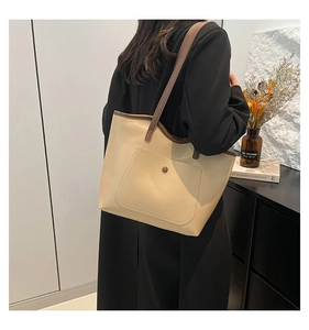 Detail of a large beige leather tote bag with contrasting brown straps for daily commute
