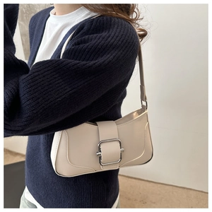 Detail of off-white baguette bag with large silver buckle on dark blue sweater