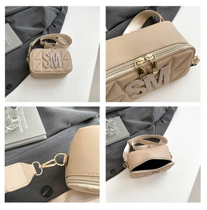Detail van beige gewatteerde tas met SM-logo, gouden hardware en brede schouderband