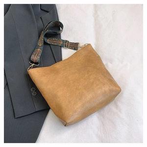 Detail of a brown leather tote bag with a decorative ethnic pattern embroidered strap