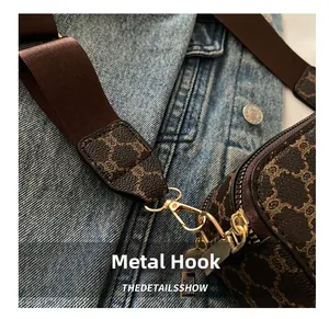Dettaglio del gancio dorato sulla borsa a tracolla in tela con motivo vintage