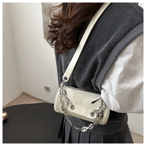 Détail du sac cylindre ivoire en cuir verni brillant avec chaîne en métal argenté