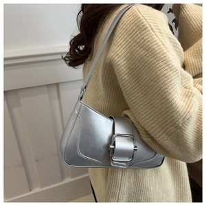 Detail of silver metallic underarm bag with oversized square buckle on beige sweater