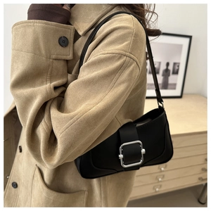 Détail d'un sac sous le bras en cuir noir mat avec une boucle en métal argenté poli