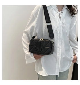 Detail van zwarte gewatteerde crossbody cameratas met brede riem en 3D SM-logo