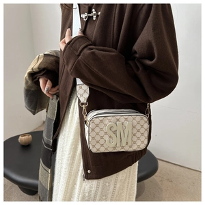 Detail of vintage crossbody camera bag with monogram pattern and gold SM logo