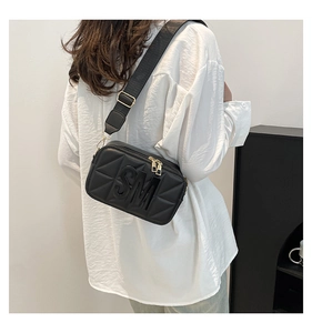 Close-up van zwarte crossbody tas met 3D-geometrische textuur en brede schouderriem