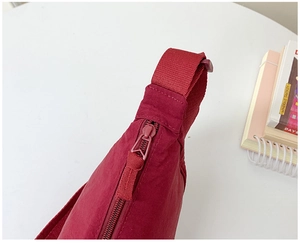 Detailed close-up of red nylon dumpling bag featuring durable zipper and webbing strap