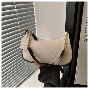 Détail de la texture cuir grainé sur sac croissant blanc cassé avec une chaîne dorée