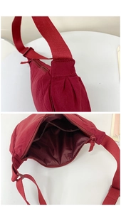 Detail view of burgundy canvas dumpling bag showing inner pocket and adjustable strap