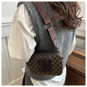 Classic camera bag in deep brown with logo detail and nylon strap on a model