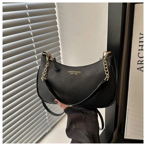 Détail du sac croissant noir grainé avec chaîne dorée et logo imprimé sur cuir