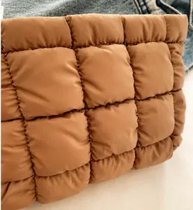 Detailed macro view of brown quilted nylon fabric with premium stitching on a handbag