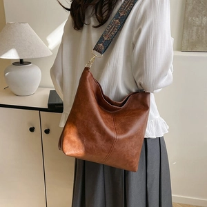 Close-up of vintage brown leather hobo bag with ethnic style blue embroidery strap
