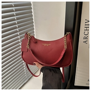 Détail d'un sac hobo rouge en cuir grainé avec chaîne dorée et logo de marque