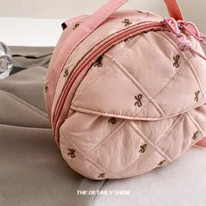 Detail of pink quilted fabric with brown bow embroidery and fine stitching texture