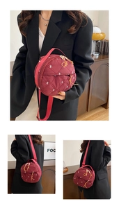 Detail of burgundy quilted round bag with white bow embroidery and double zippers
