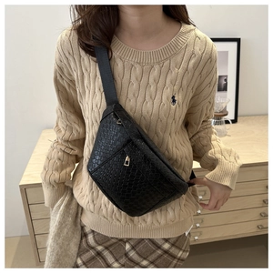 Detail showing woven texture and golden zipper on this black crossbody chest bag
