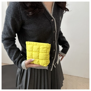 Macro view of bright yellow quilted cosmetic bag with puffy texture and gold metal zipper