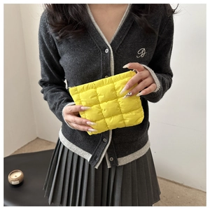 Detailansicht der leuchtend gelben gesteppten Nylon-Kosmetiktasche, von einer Person gehalten