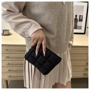 Detail einer schwarzen gesteppten Puffer-Clutch aus Nylon in der Hand eines Models