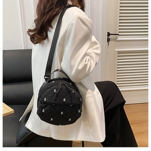Close-up of black round crossbody bag with white bow embroidery and diamond quilting