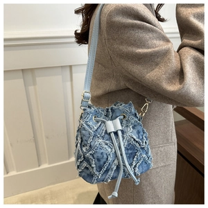 Detail of blue denim patchwork bucket bag with frayed edges and drawstring closure