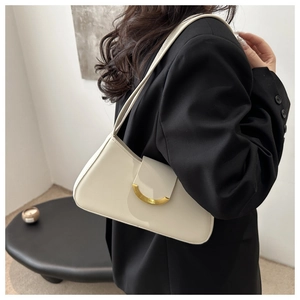 Detalle de un bolso de hombro en cuero blanco crema con hebilla dorada en el modelo