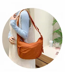 Detail of terracotta nylon hobo bag with textured fabric and woven zipper puller