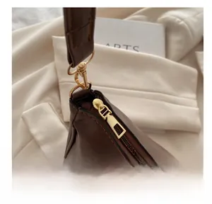 Detail shot of smooth gold-tone zipper and fine stitching on the brown shoulder bag