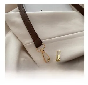 Detail shot of vintage brown leather bag with golden metal hook and zipper hardware