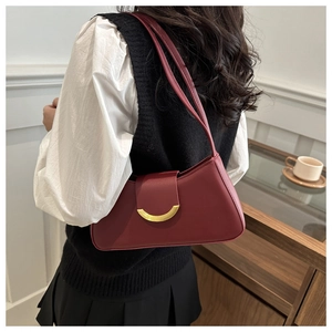Modelo con bolso de hombro color vino tinto y elegante cierre dorado en detalle