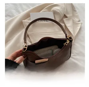 Detail showing inner capacity of dark brown leather crescent bag with daily essentials