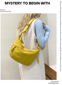 Detail of a bright yellow nylon crescent bag with woven zipper pulls and adjustable strap