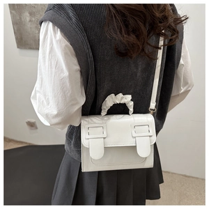 Détail d'un sac à bandoulière blanc avec une poignée plissée au design de nuage