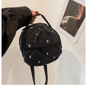 Detail of black round quilted crossbody bag with delicate bow embroidery and top handle