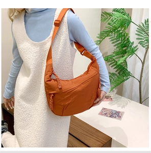 Detailed side view of an orange crescent crossbody bag with adjustable shoulder strap