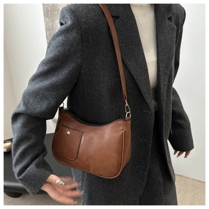 Close-up of brown faux leather crescent bag with gold buckle and adjustable strap