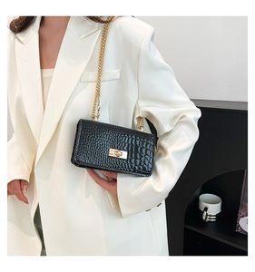 Detailed view of black crocodile pattern leather with gold chain strap on a crossbody bag