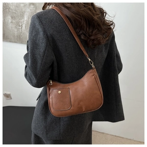 Close-up of brown PU leather shoulder bag with gold zipper detail on grey coat
