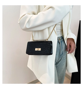 Detail of black patent leather crossbody bag with crocodile pattern and gold chain
