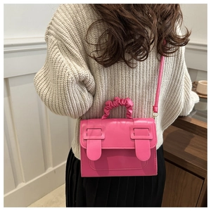 Détail d'un mini sac rose fuchsia avec rabat à deux boucles et poignée à effet plissé