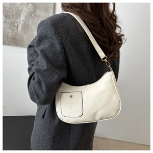 Detail der minimalistischen beigen Halbmond-Schultertasche am Model in grauem Tweed-Blazer
