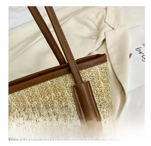 Detail of straw tote bag showing reinforced leather handles and woven texture craft