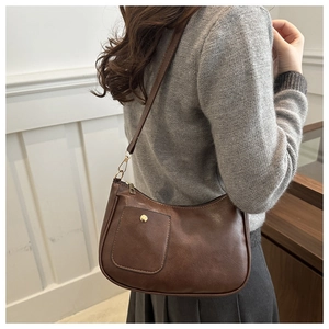 Detail of dark brown matte leather shoulder bag featuring a gold button front pocket