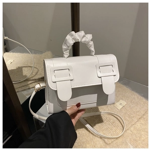 Détail du sac carré blanc avec poignée froncée nuage sur un tapis blanc en peluche