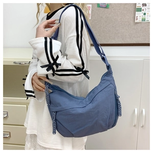 Detail of navy blue nylon hobo bag featuring woven rope zipper pulls and a wide shoulder strap