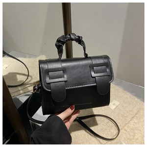 Détail d'un mini sac noir vintage avec poignées plissées et doubles boucles carrées