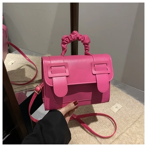 Détail du sac bandoulière rose fuchsia avec poignée plissée et boucles carrées