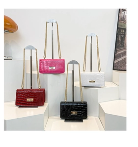 Detail view of four crocodile-embossed glossy leather handbags with gold chain straps